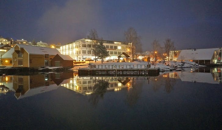 Oselvarverkstaden (t.v.) Oselvarnaustet (t.h.) spegla seg i Os hamn tysdag kveld. (Foto: Kjetil Vasby Bruarøy)